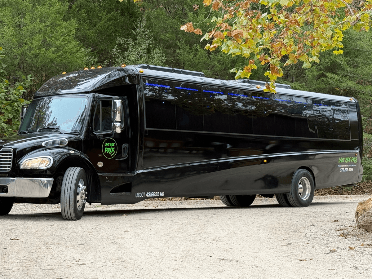 Lake Ride Pros luxury transportation fleet lined up at Lake of the Ozarks including limo bus, Rescue Squad truck, SUVs, and Mercedes Sprinter vans with lake view in background